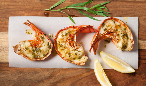 Freshly caugh lobster tails cooked with slice of lemon on platter